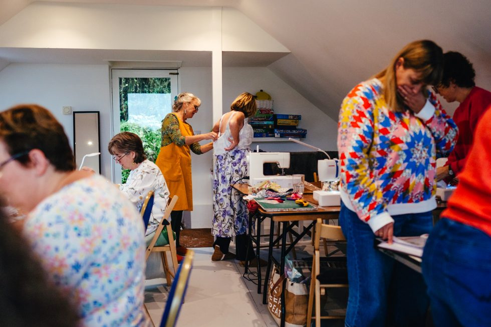 Sewing studio full of ladies sewing, fitting clothes and discussing ideas